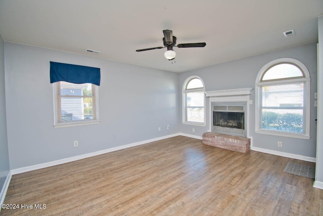 unfurnished living room with ceiling fan, light wood-type flooring, and a brick fireplace