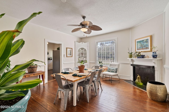 dining area with a textured ceiling, ceiling fan, and dark wood-type flooring