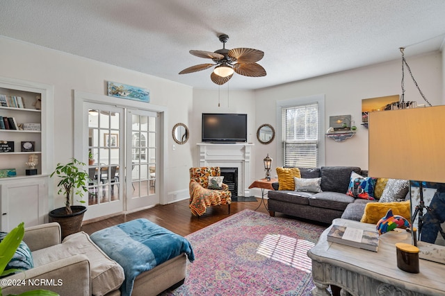 living room featuring built in shelves, a textured ceiling, hardwood / wood-style flooring, and ceiling fan