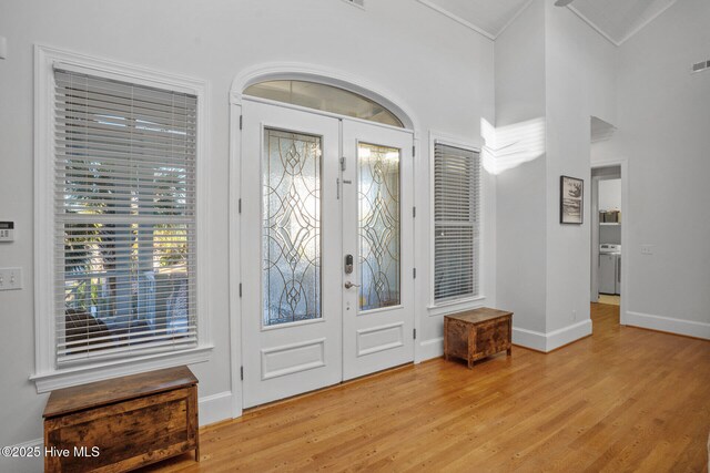 living room with ceiling fan, a high ceiling, built in features, light hardwood / wood-style floors, and a fireplace