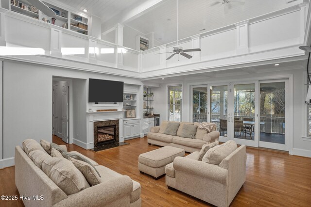 living room featuring built in shelves, a fireplace, beamed ceiling, and light hardwood / wood-style flooring