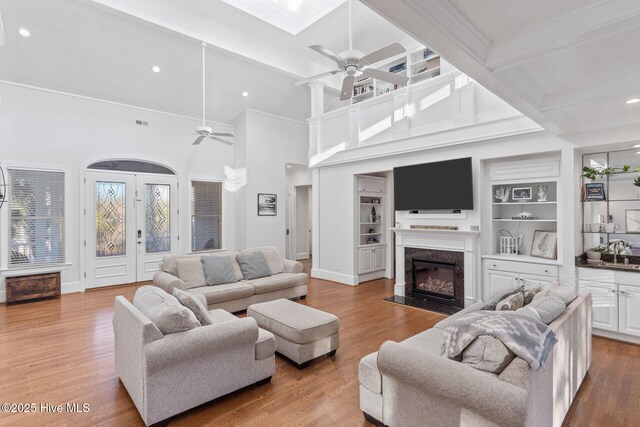 living room with a towering ceiling, hardwood / wood-style flooring, ceiling fan, and crown molding