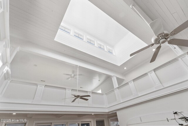 living room featuring built in shelves, ceiling fan, a premium fireplace, light hardwood / wood-style floors, and ornamental molding