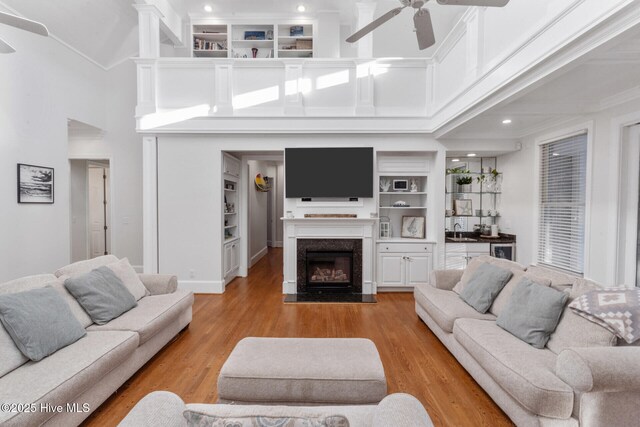 kitchen with kitchen peninsula, white cabinetry, stainless steel refrigerator, and wall chimney range hood