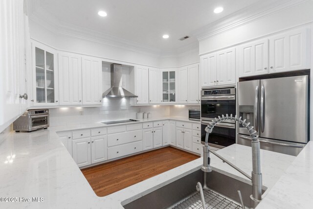 kitchen featuring decorative backsplash, white cabinetry, double oven, and wall chimney exhaust hood