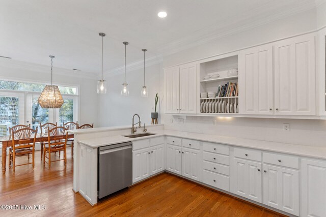 kitchen featuring appliances with stainless steel finishes, sink, pendant lighting, light hardwood / wood-style flooring, and white cabinetry