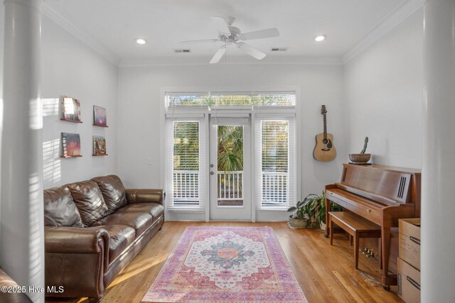 living room with ornate columns, ceiling fan, crown molding, and wood-type flooring