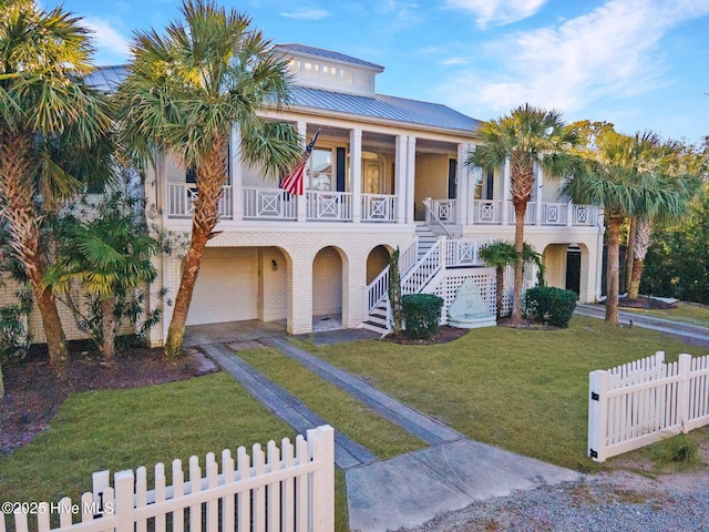 view of front of property featuring covered porch, a garage, and a front lawn