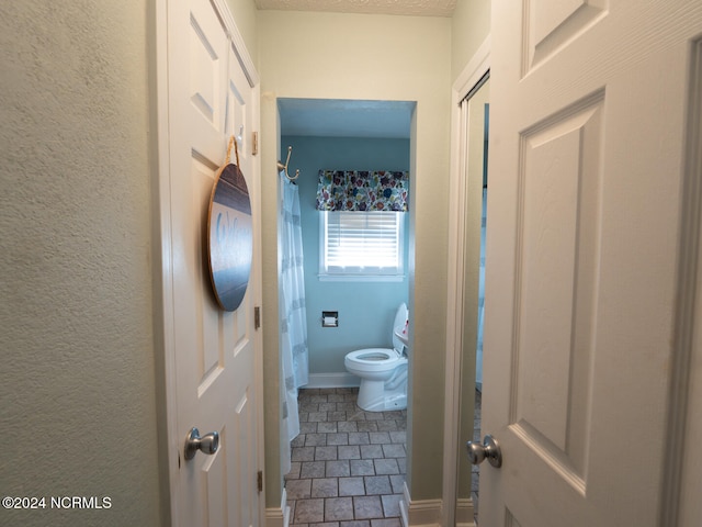 bathroom with toilet, walk in shower, and tile patterned flooring