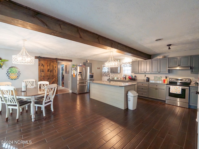 kitchen with a center island with sink, appliances with stainless steel finishes, a barn door, dark hardwood / wood-style floors, and gray cabinetry