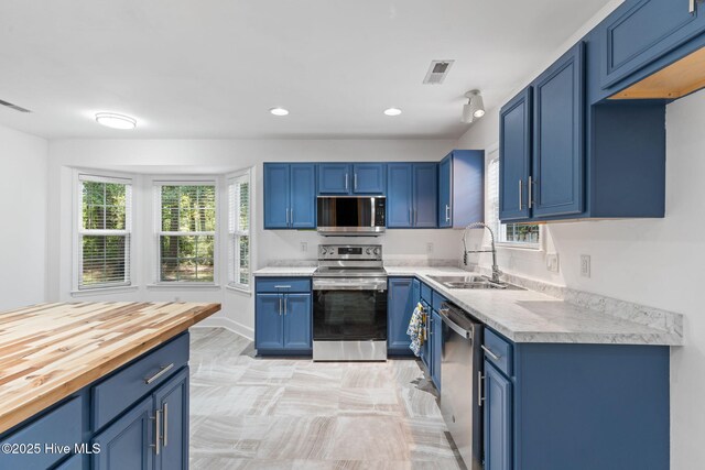 8525 Primm Forest Dr, Leland, NC 28451 - kitchen featuring appliances with stainless steel finishes, a sink, blue cabinetry, recessed lighting, and baseboards