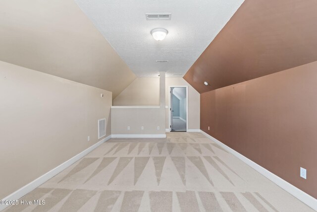 8525 Primm Forest Dr, Leland, NC 28451 - additional living space featuring a textured ceiling, visible vents, baseboards, light colored carpet, and vaulted ceiling