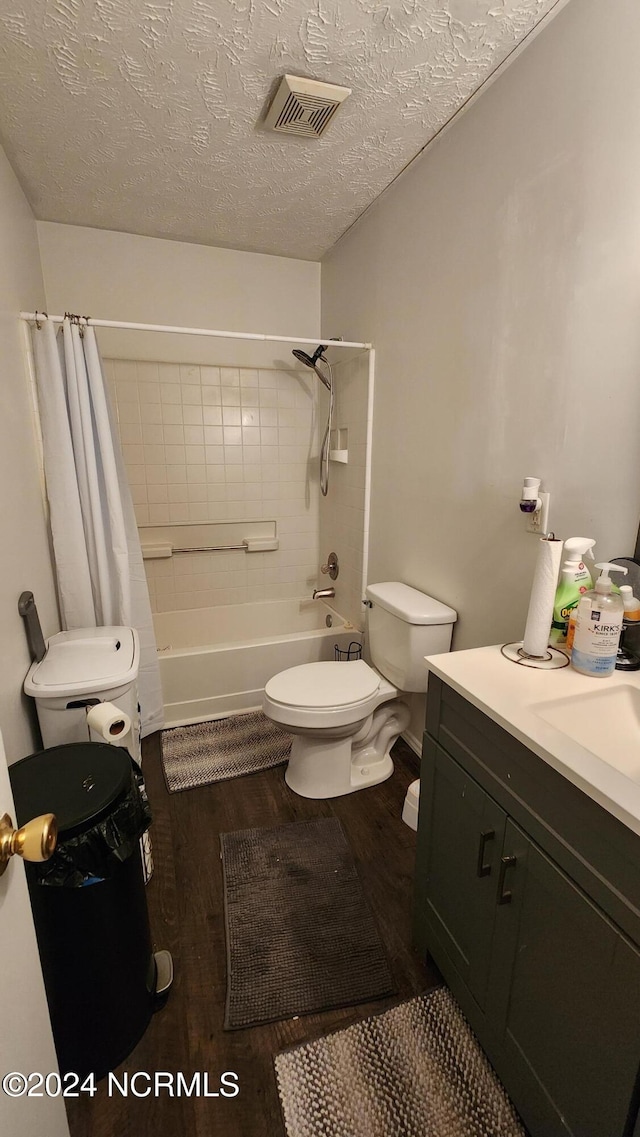 full bathroom with vanity, shower / bath combination with curtain, a textured ceiling, and toilet