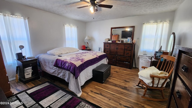 bedroom with ceiling fan, a textured ceiling, and dark hardwood / wood-style flooring