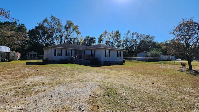 ranch-style home featuring a storage unit and a front lawn