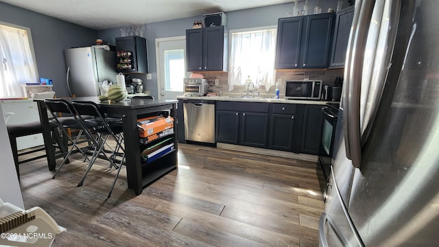 kitchen with sink, decorative backsplash, appliances with stainless steel finishes, and dark hardwood / wood-style flooring