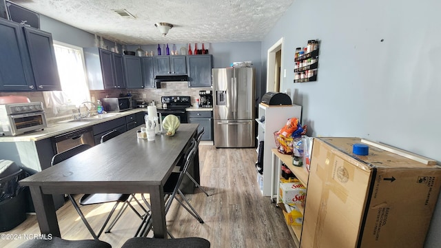 kitchen with light wood-type flooring, fridge, a textured ceiling, electric range, and stainless steel refrigerator with ice dispenser