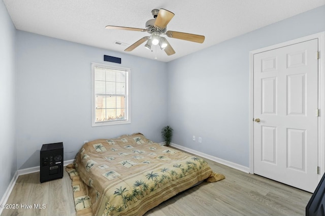 bedroom featuring ceiling fan, a textured ceiling, and light hardwood / wood-style flooring