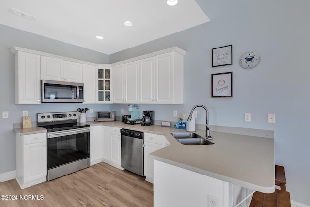 kitchen featuring stainless steel appliances, sink, kitchen peninsula, and white cabinets