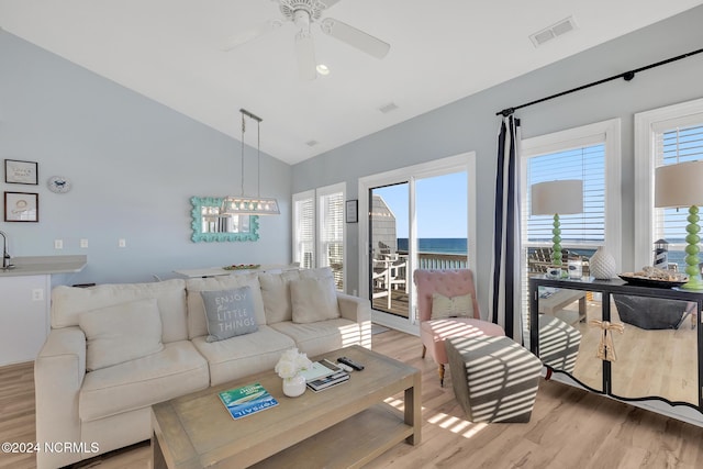 living room with light wood-type flooring, a water view, a healthy amount of sunlight, and ceiling fan