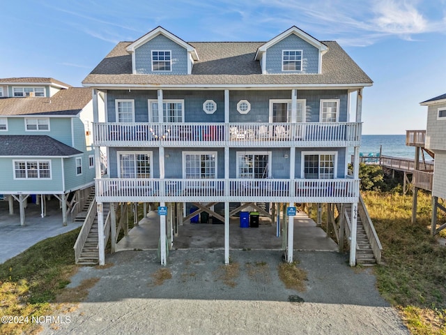 raised beach house featuring a water view, a carport, and a balcony