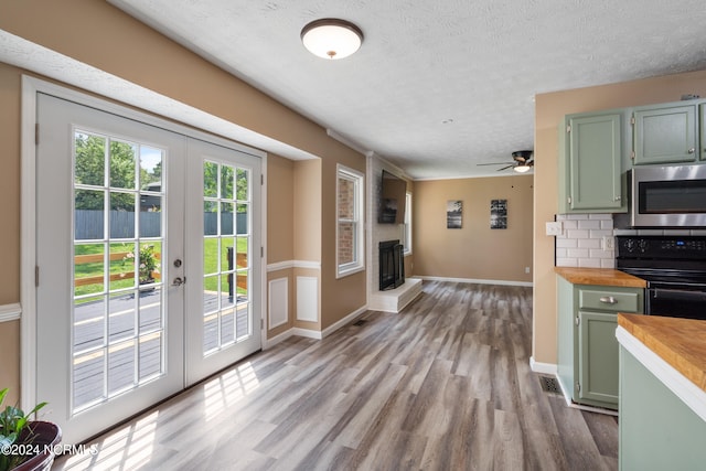 kitchen with oven, decorative backsplash, light hardwood / wood-style flooring, french doors, and butcher block countertops