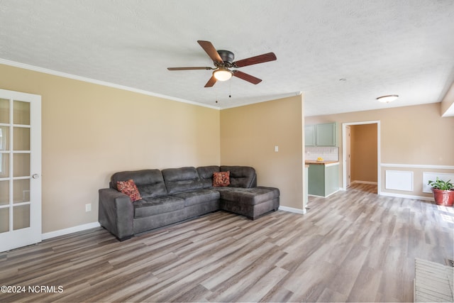 living room with light hardwood / wood-style floors, ornamental molding, a textured ceiling, and ceiling fan