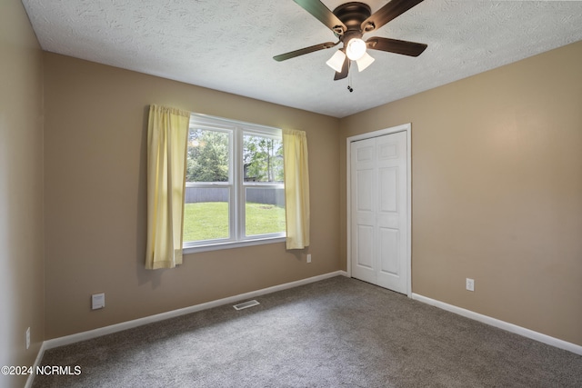 spare room with a textured ceiling, carpet flooring, and ceiling fan