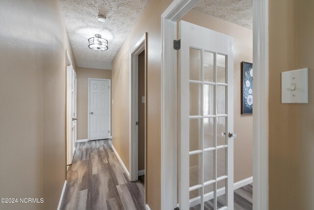 hall with hardwood / wood-style flooring and a textured ceiling