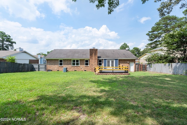 rear view of house with french doors, a deck, and a lawn