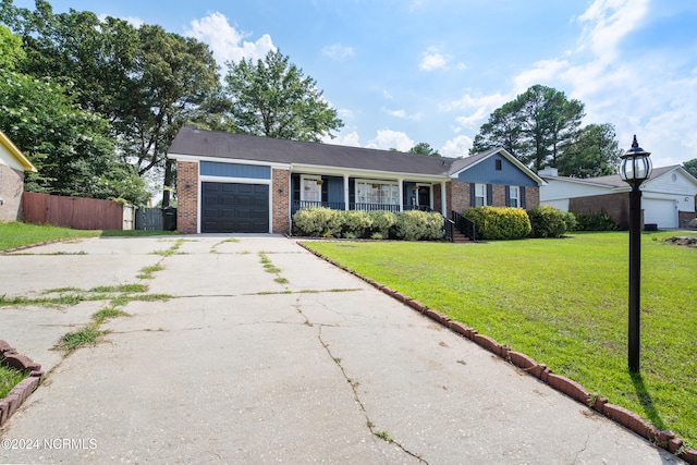 ranch-style home featuring covered porch, a front yard, and a garage