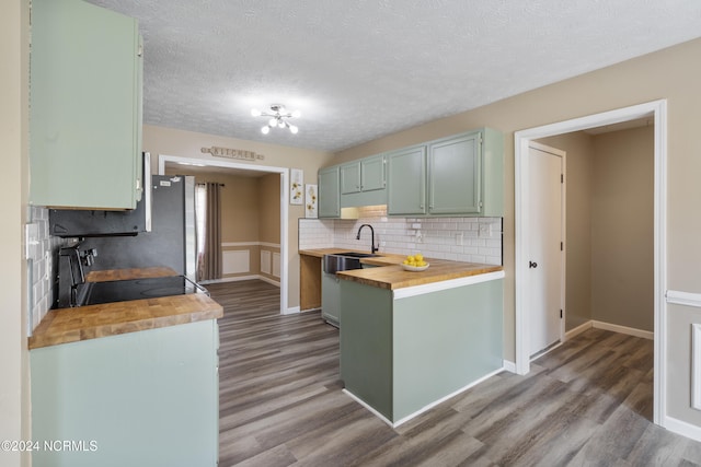 kitchen with hardwood / wood-style floors, tasteful backsplash, a textured ceiling, range, and wooden counters