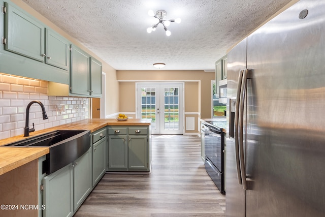 kitchen featuring wooden counters, french doors, stainless steel refrigerator with ice dispenser, black electric range, and light hardwood / wood-style floors