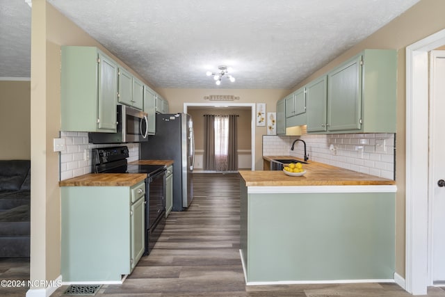 kitchen featuring butcher block counters, green cabinets, sink, appliances with stainless steel finishes, and dark hardwood / wood-style flooring