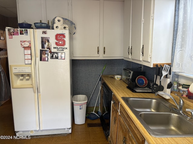 kitchen featuring white refrigerator with ice dispenser, tasteful backsplash, white cabinetry, black dishwasher, and sink