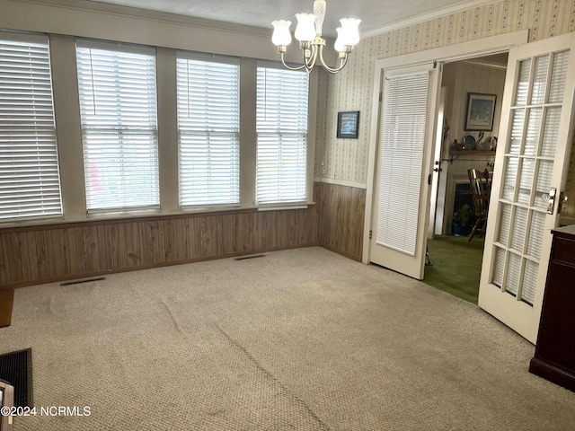 unfurnished dining area with an inviting chandelier, crown molding, light carpet, and plenty of natural light