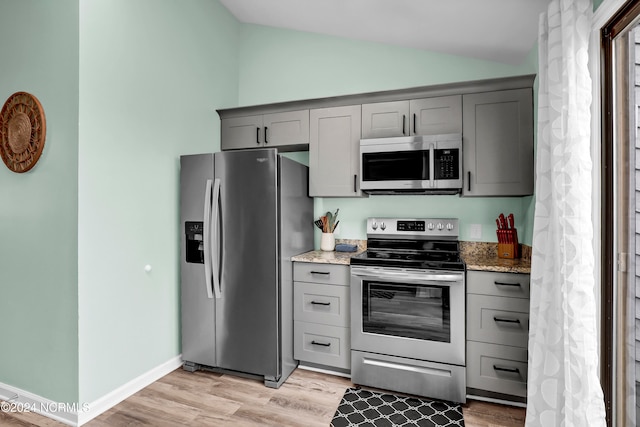 kitchen featuring appliances with stainless steel finishes, gray cabinetry, vaulted ceiling, and light hardwood / wood-style floors