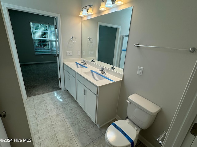 bathroom with toilet, vanity, and tile patterned floors