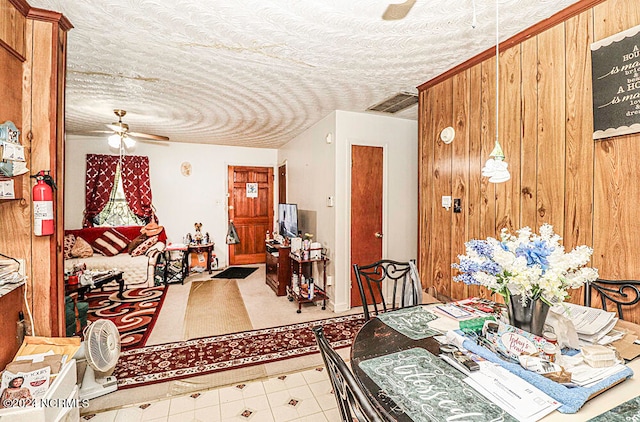 dining room featuring ceiling fan, a textured ceiling, and wooden walls