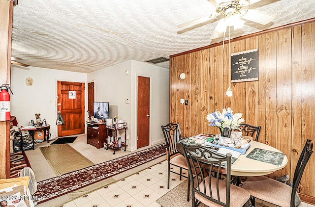 dining room with ceiling fan and wooden walls