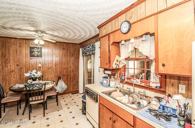 kitchen with dishwasher, wooden walls, sink, and ceiling fan