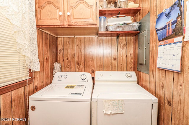 washroom with cabinets, wood walls, electric panel, and washer and clothes dryer