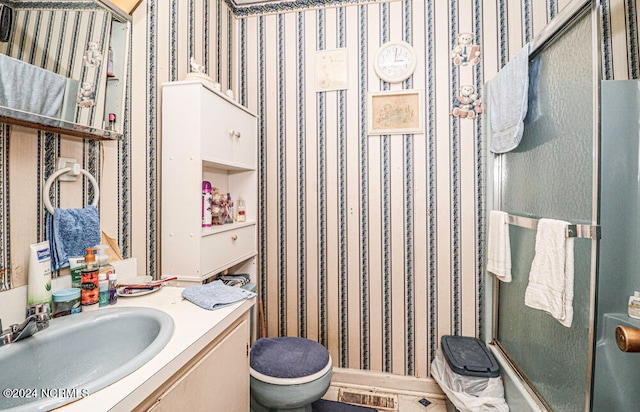 bathroom with vanity, toilet, and a shower with door