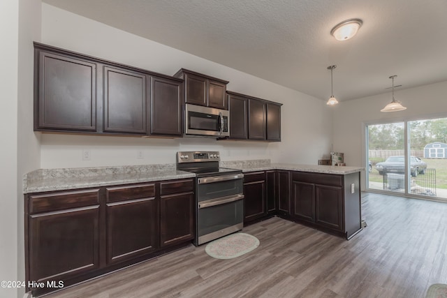 kitchen featuring dark brown cabinetry, light wood-type flooring, appliances with stainless steel finishes, and decorative light fixtures