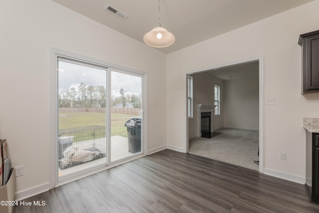 unfurnished dining area featuring a textured ceiling and dark hardwood / wood-style floors