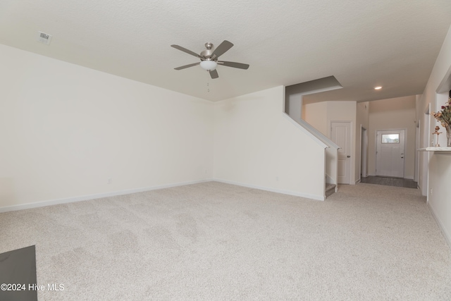 carpeted spare room with ceiling fan and a textured ceiling