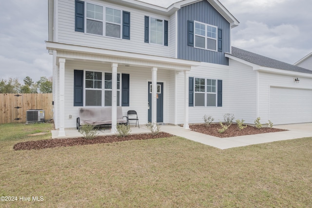 view of front of property featuring covered porch, a garage, a front yard, and central AC