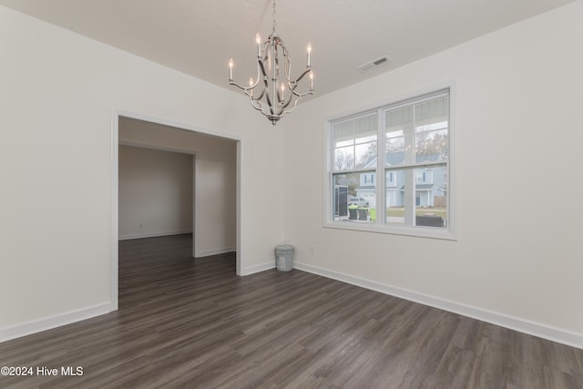 unfurnished dining area featuring dark wood-type flooring, a chandelier, and a textured ceiling