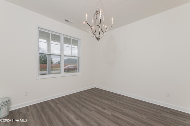 unfurnished room with dark wood-type flooring, a chandelier, and a textured ceiling