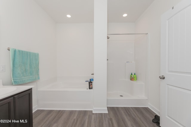 bathroom featuring wood-type flooring, vanity, and plus walk in shower